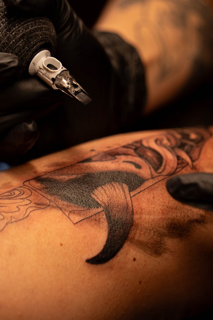 services-04 Tattoo artist creating intricate tattoo design on arm in close-up.