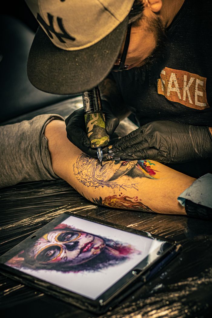 about-img Tattoo artist working on a detailed arm tattoo in a Ciudad de México studio.